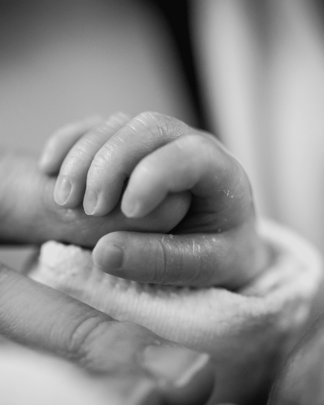 A baby’s hand held gently by an adult